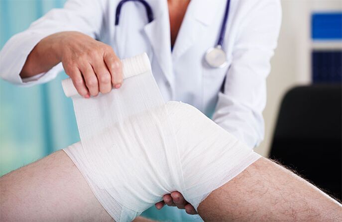 doctor bandaging knee joint with arthrosis